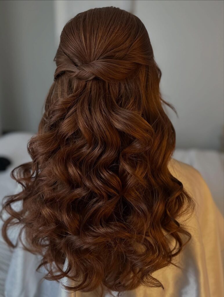 Long curly brown hair styled half up with volume at the crown and defined curls cascading down.