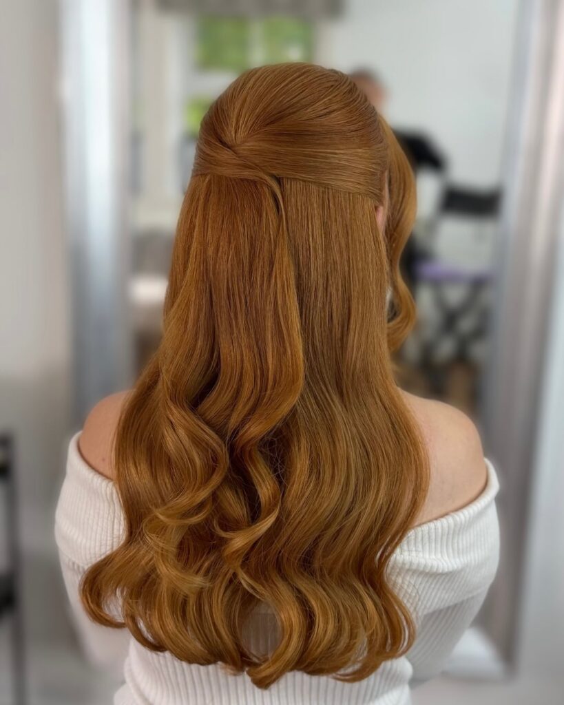 Long copper hair styled in a sleek half up twist with soft loose waves.