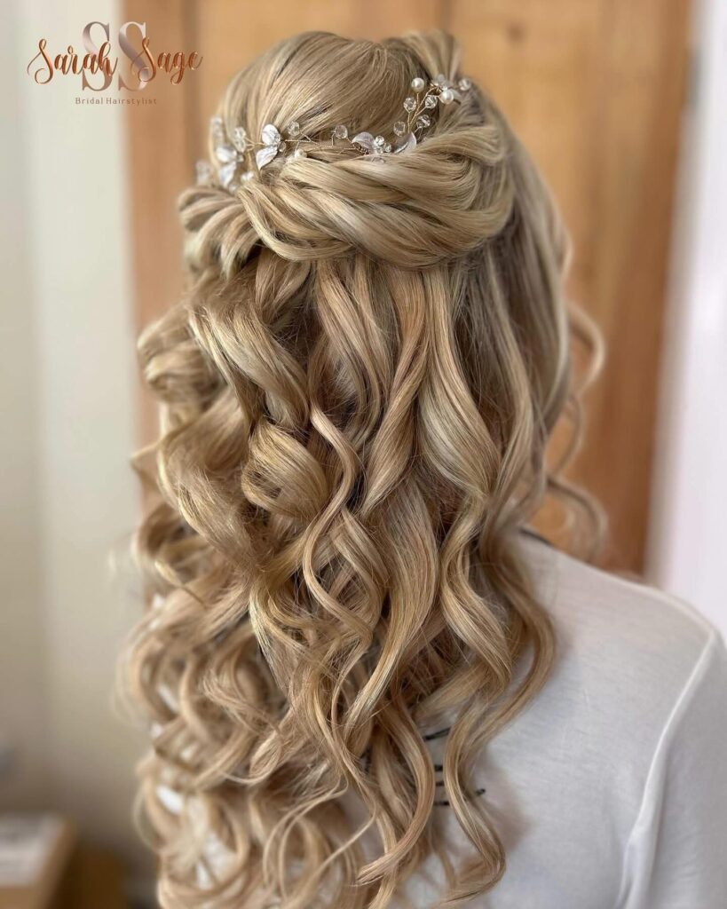 Long blonde curly hair styled with a twisted crown and crystal hairpiece with soft cascading curls.