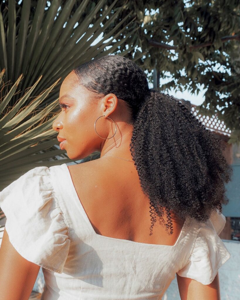 Sleek ponytail with laid edges and a voluminous curly natural hair tail.