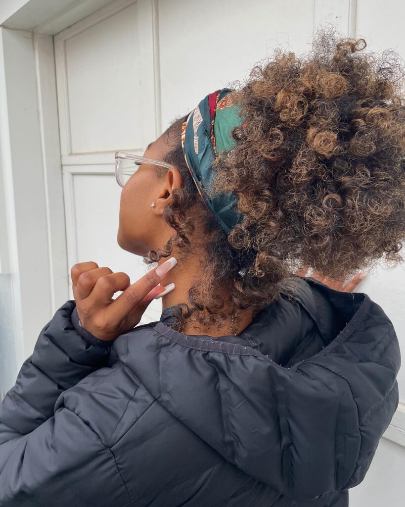 Curly puff ponytail with a headband and highlighted natural curls.