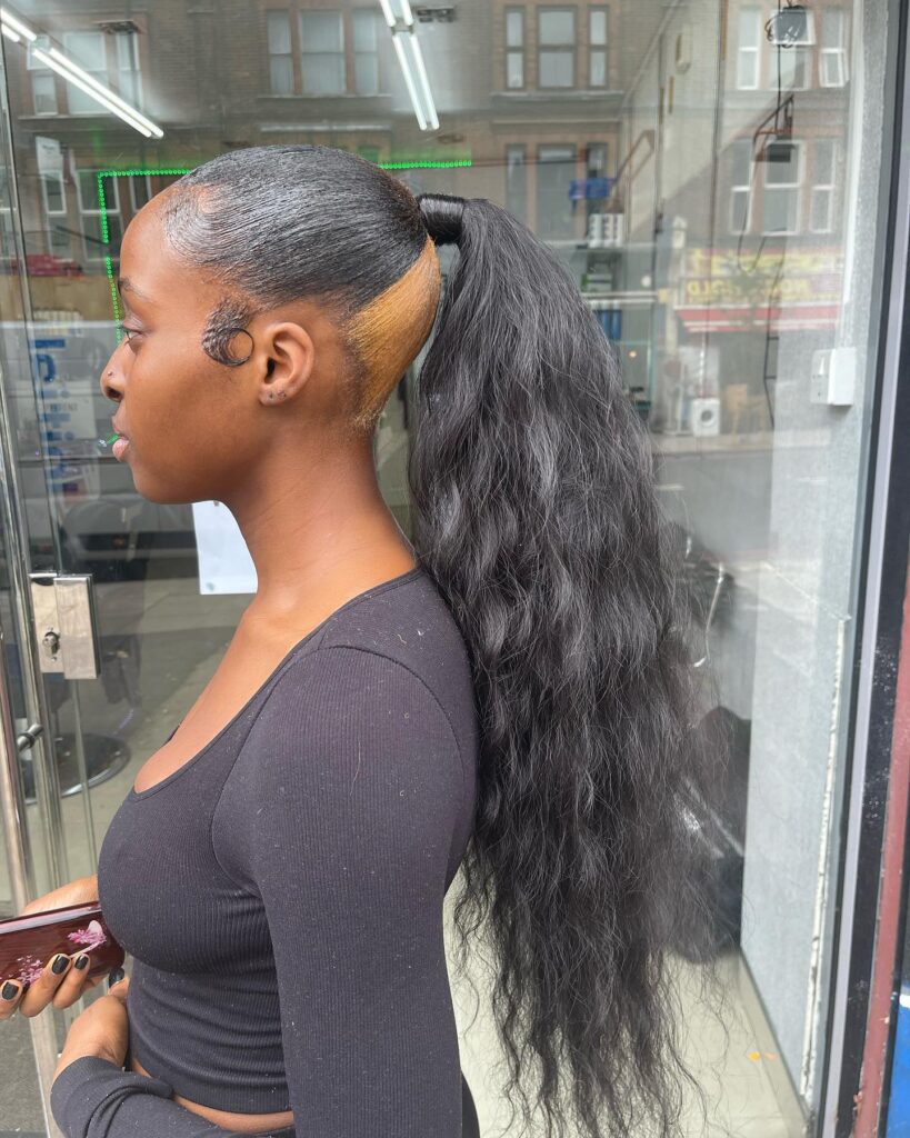 Sleek high ponytail with a long wavy tail and a colored undercut.