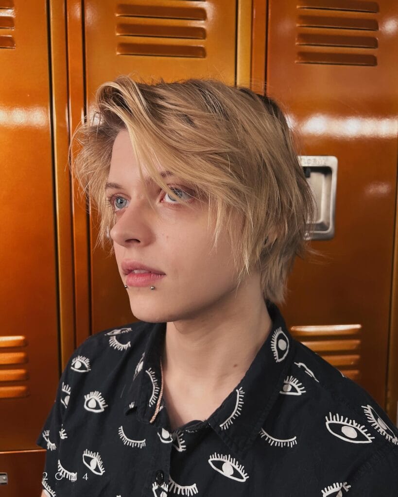 A woman with a short blonde tomboy bob featuring soft layers and a side swept fringe.