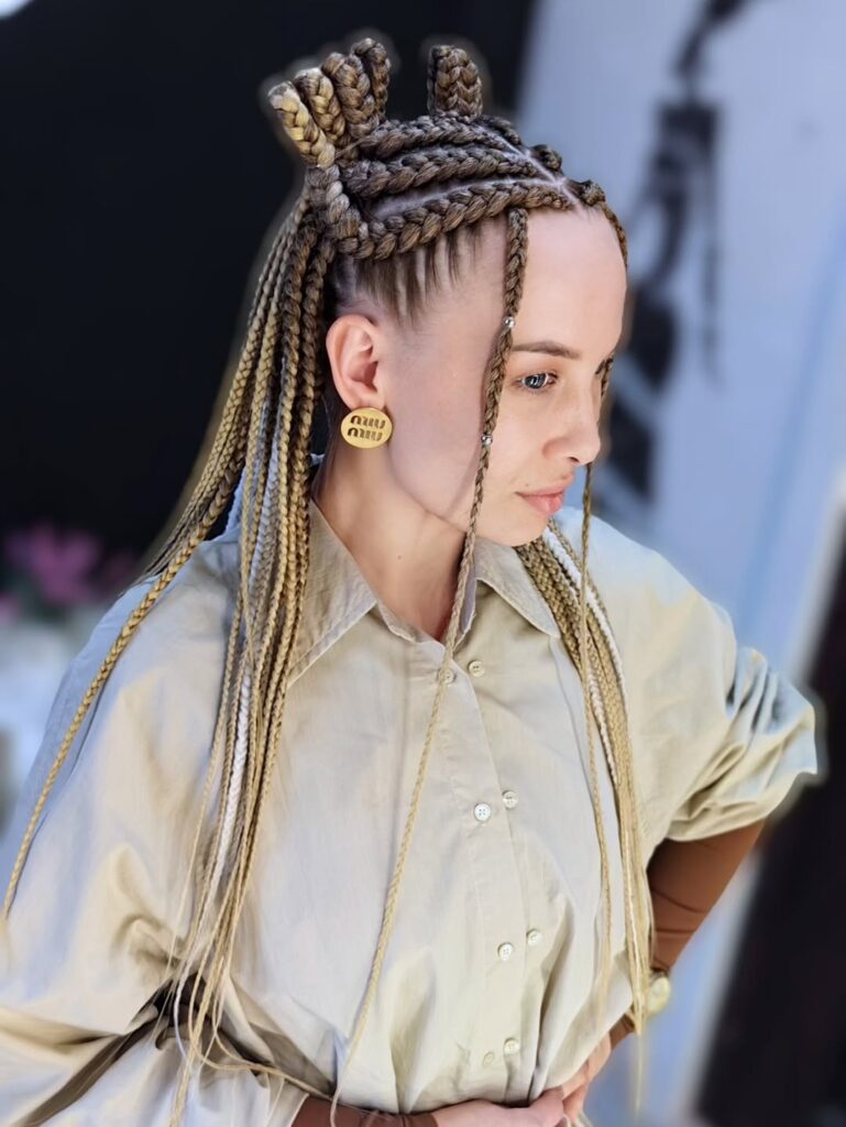 Long blonde box braids styled with two small top knots and sleek braided lengths falling down.