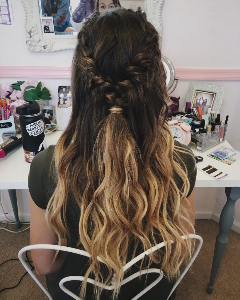 Half up braided crown with long ombre wavy hair transitioning from dark roots to blonde ends.