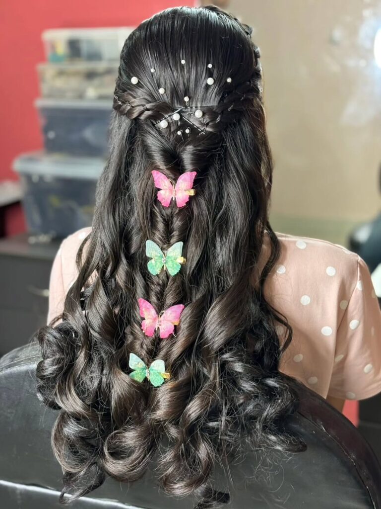 Half up braided hairstyle with long curled hair decorated with colorful butterfly clips.