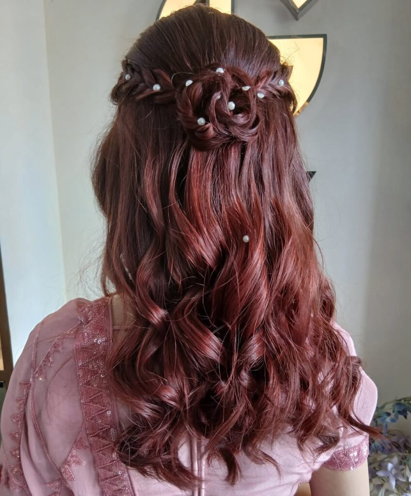 Half up braided rosette with long auburn curls and small pearl accents.