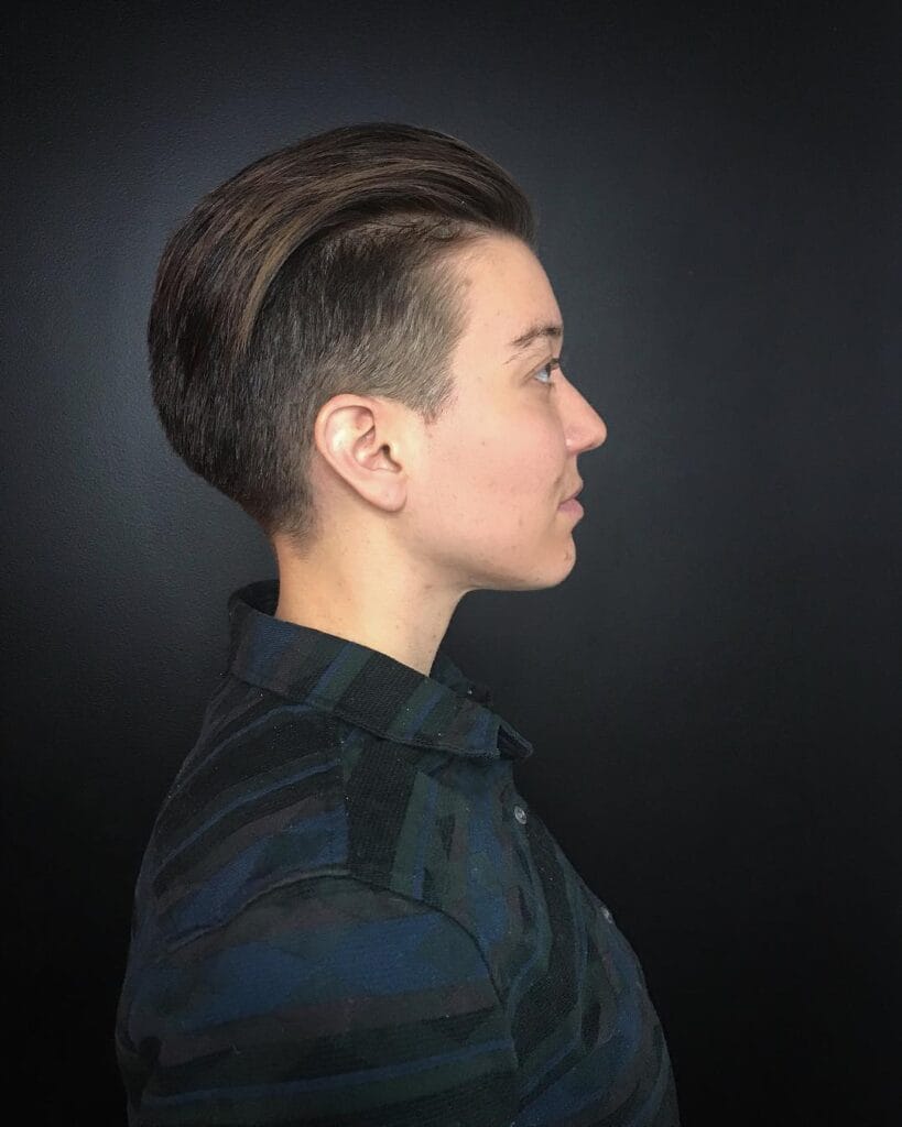 A short textured tomboy haircut with a soft choppy top and short fringe in a warm brown shade.