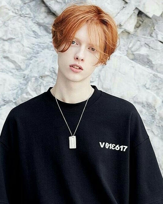 A short tomboy bob with a middle part, soft layers, and a warm copper hair color.