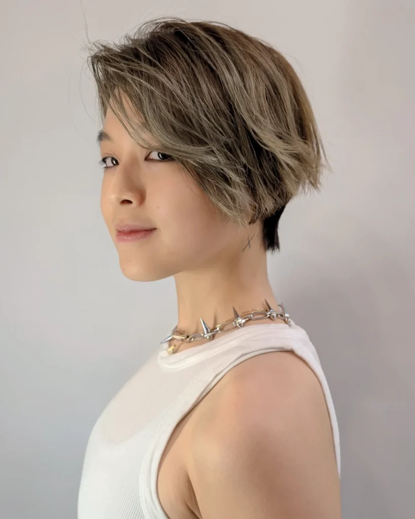 A short tomboy bob with a subtle undercut, soft layers, and a side swept ash brown finish.