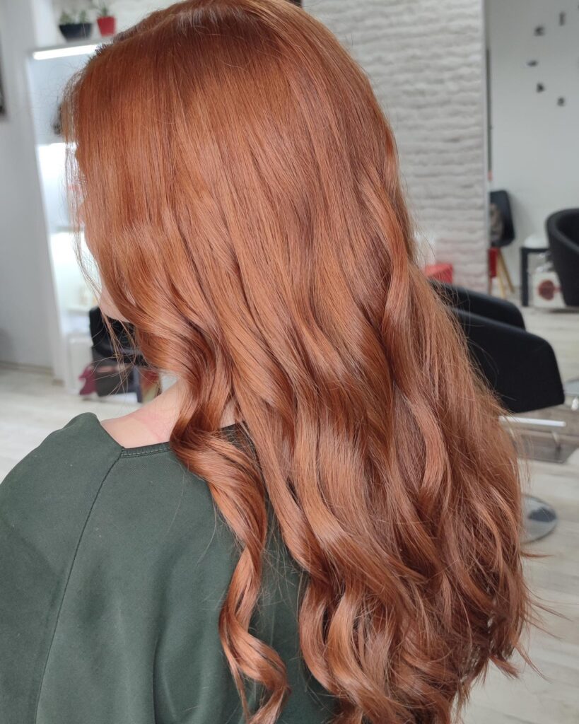 Long copper hair styled in soft natural waves with a loose and effortless finish.