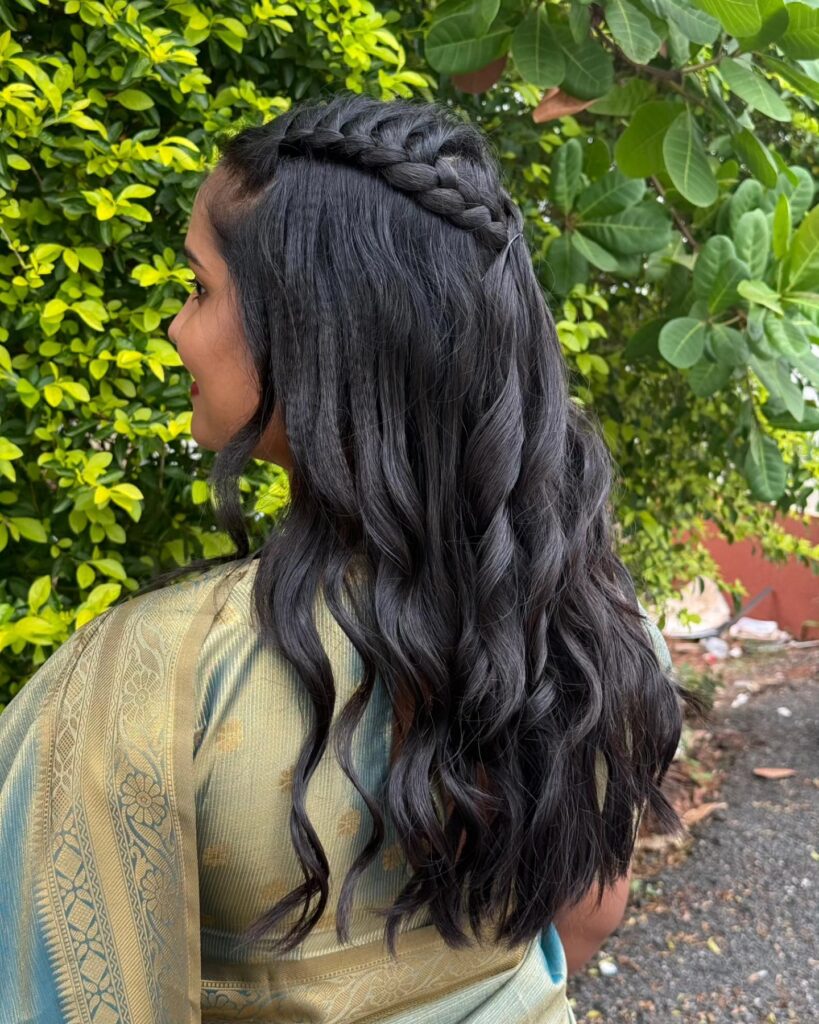 Long dark hair with a braided crown and loose soft curls cascading down the back.