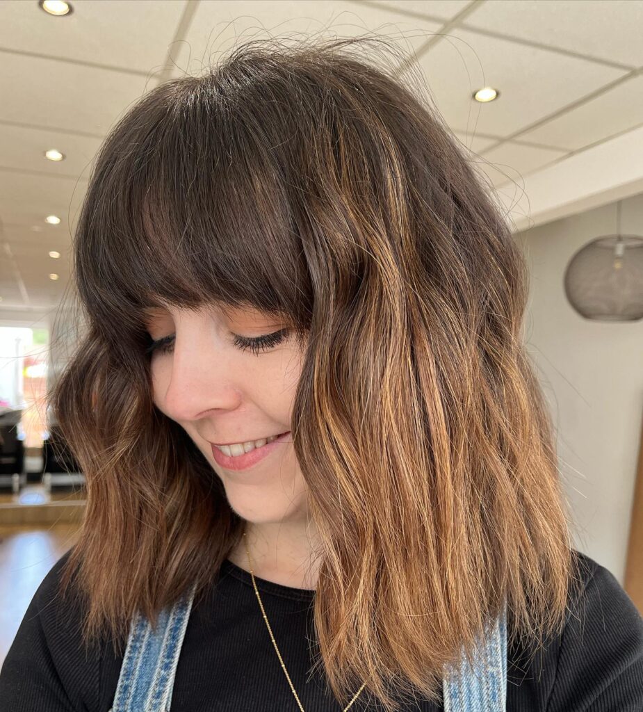 A layered brunette bob with full soft bangs and natural movement.