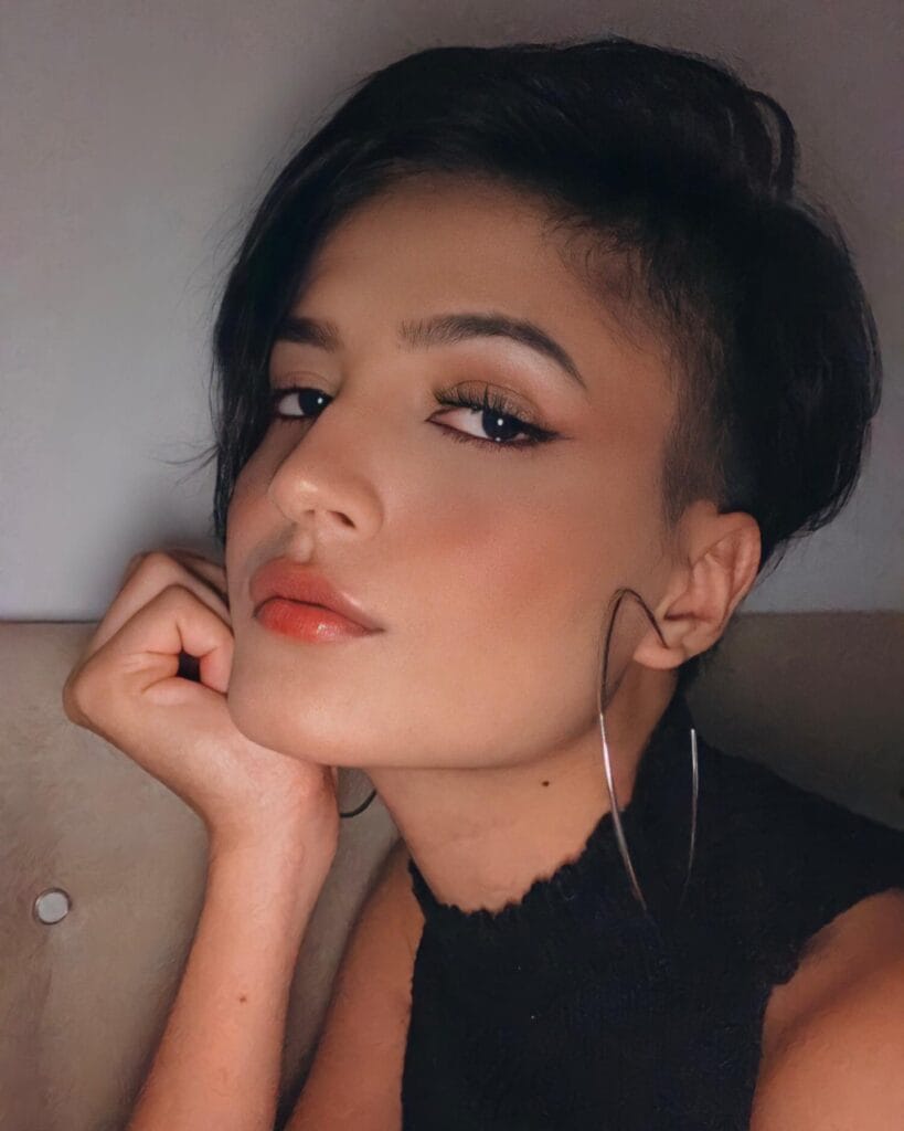 A sleek tomboy undercut with a deep side part and longer dark hair swept to one side.