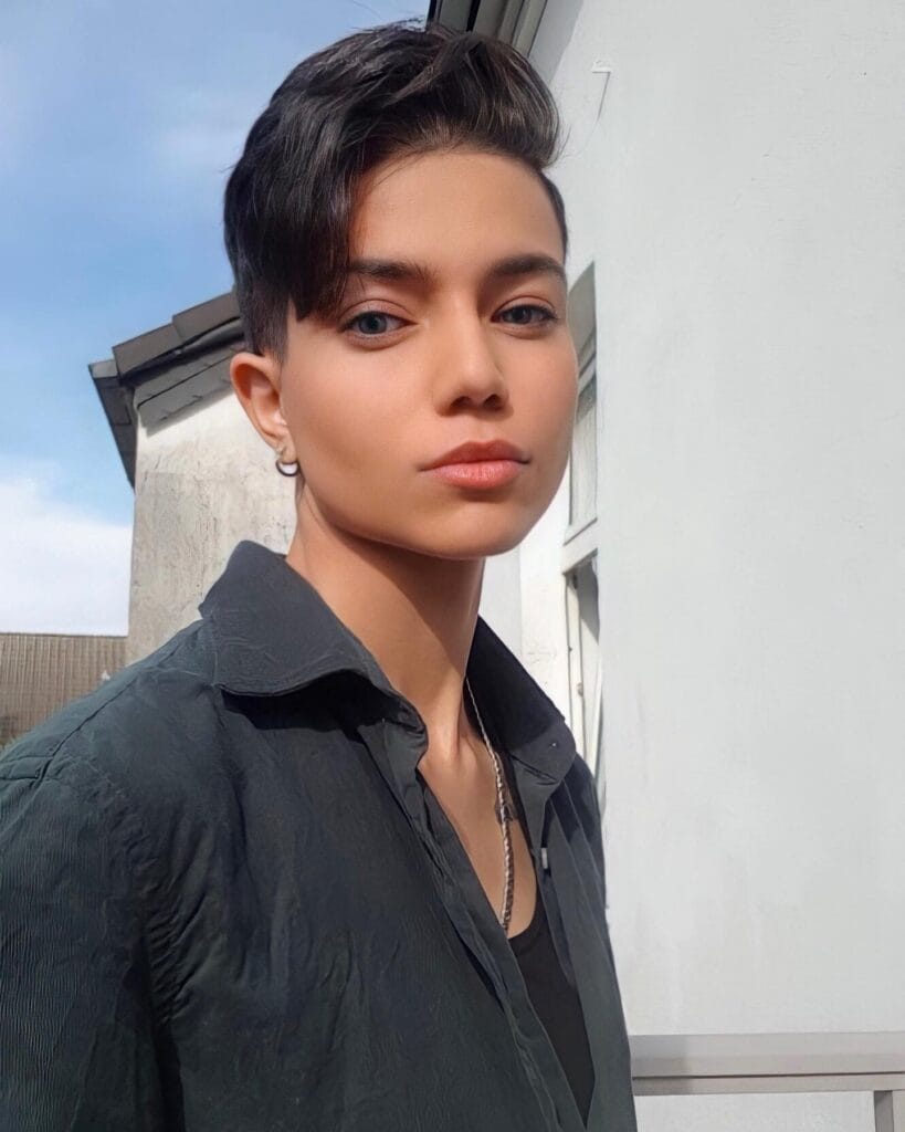 A short brunette tomboy pixie with tapered sides and a longer side swept top.