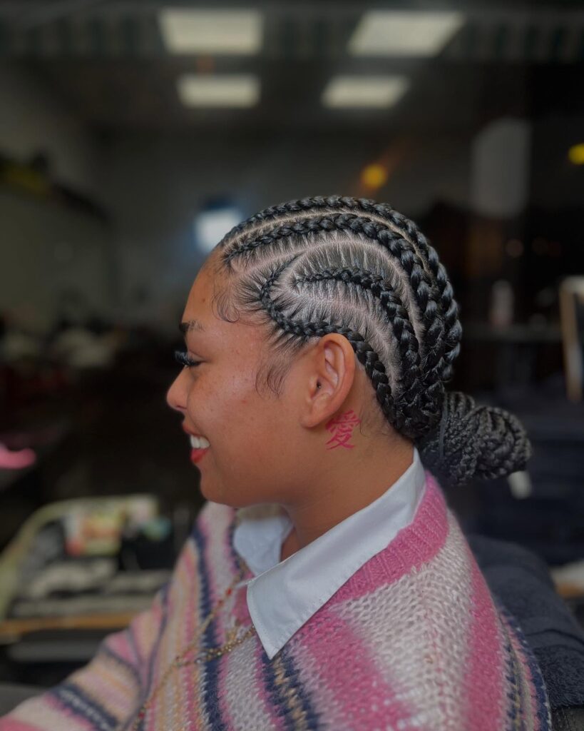 Curved cornrows styled into a low braided bun at the back of the head.
