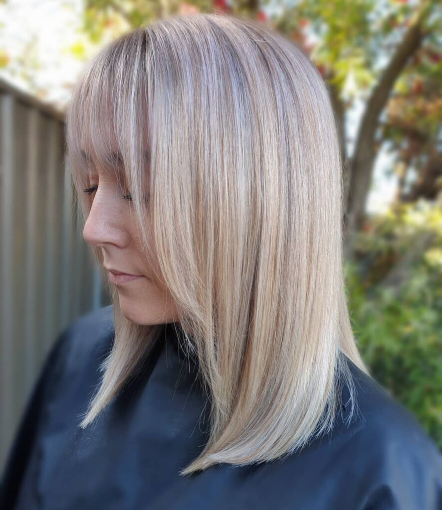 Shoulder length blonde lob with soft feathered bangs and smooth tapered ends.