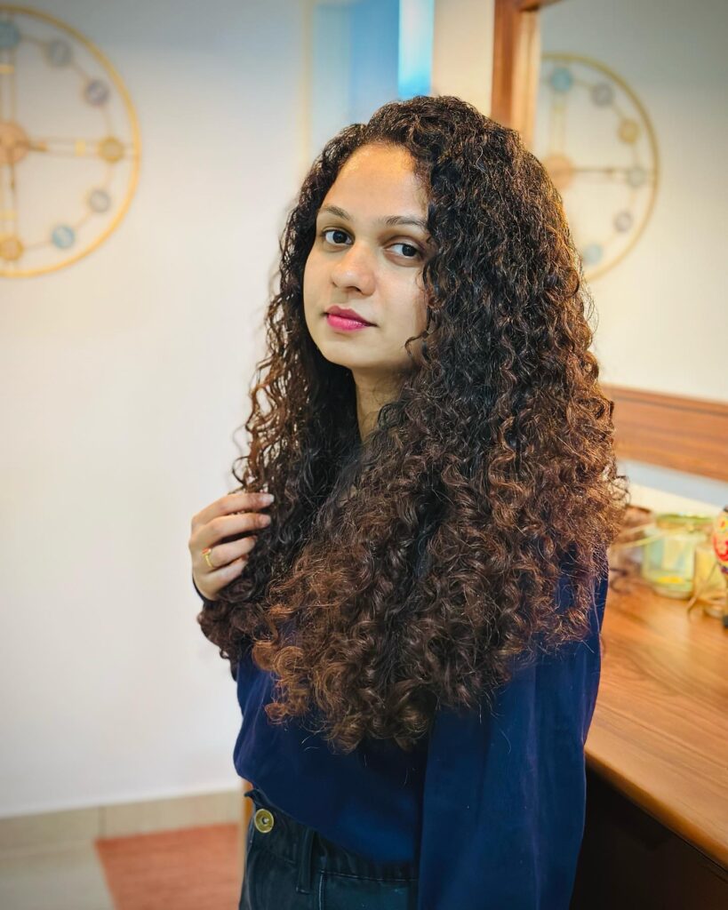 A woman with long natural curly hair in a soft loose texture with gentle volume and definition.