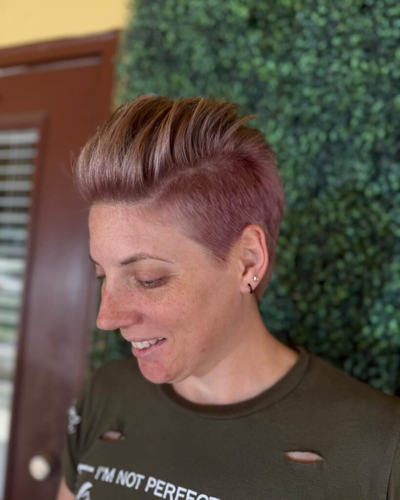Short tomboy undercut with shaved sides and a voluminous pompadour top in a soft rose tone.