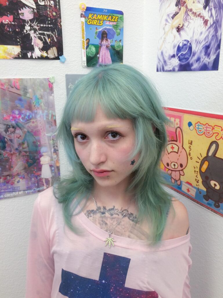 A woman with a pastel green wolf cut featuring choppy layers and full blunt bangs.