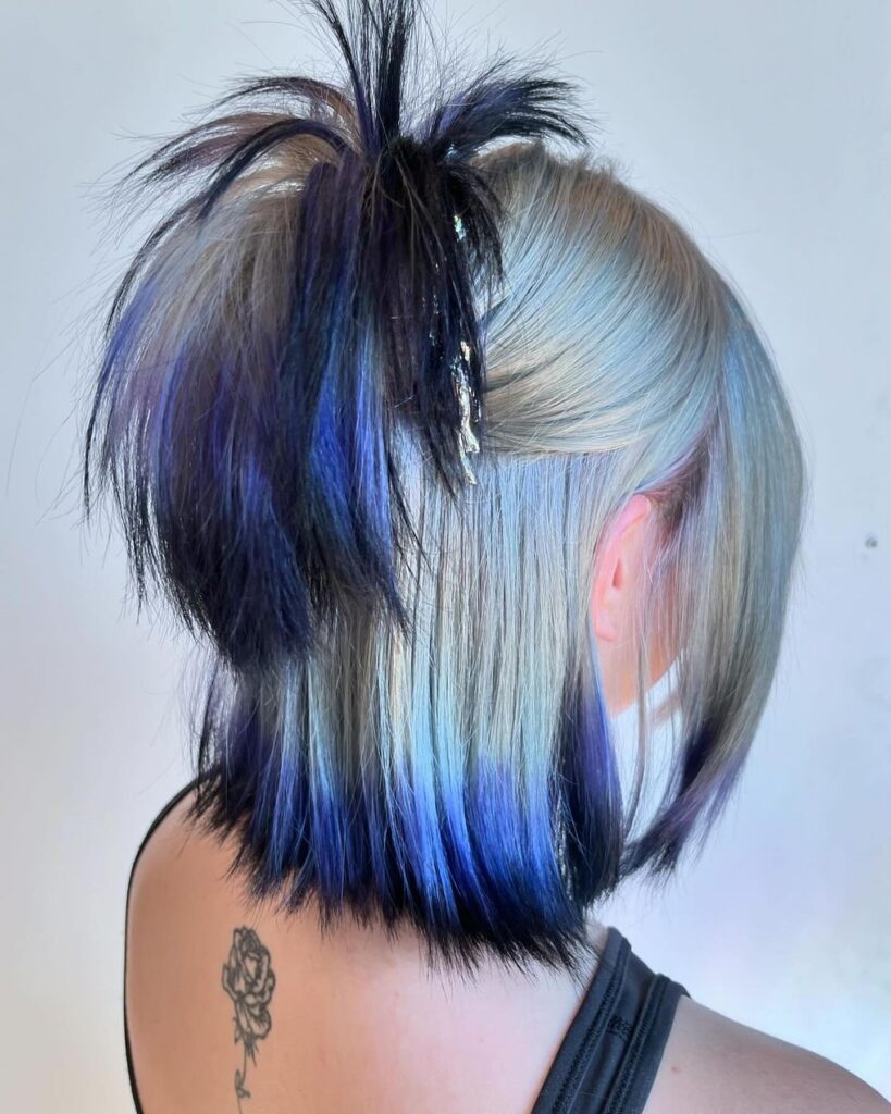 A woman with a blonde bob featuring hidden blue and black peekaboo highlights underneath.