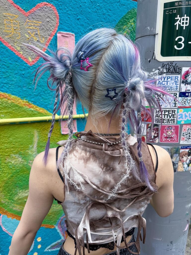 A woman with pastel blue space buns featuring star hair clips and yarn wrapped braids.