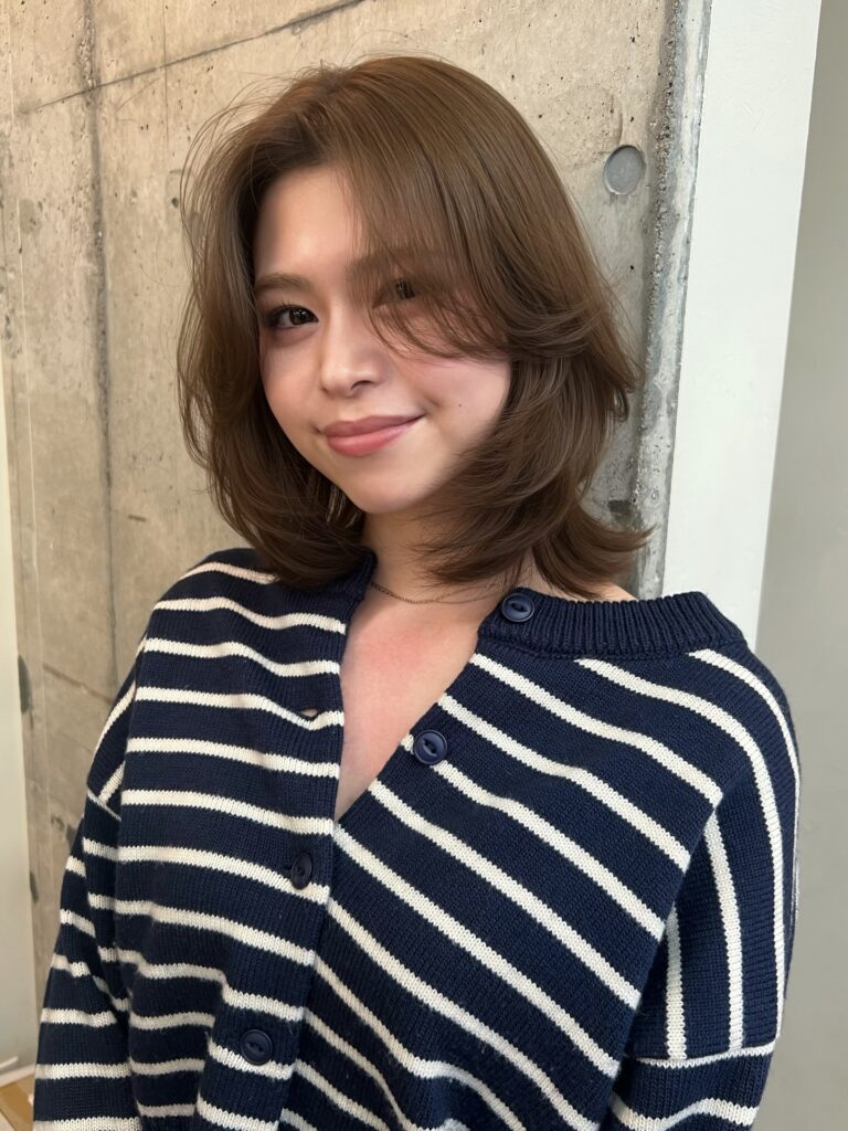 Chin length brown lob haircut with soft flipped layers and side swept bangs.