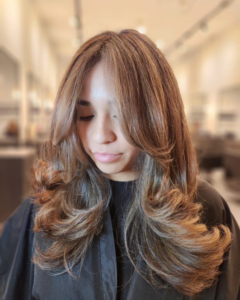 brown hair with caramel balayage and bouncy curled under layered ends.