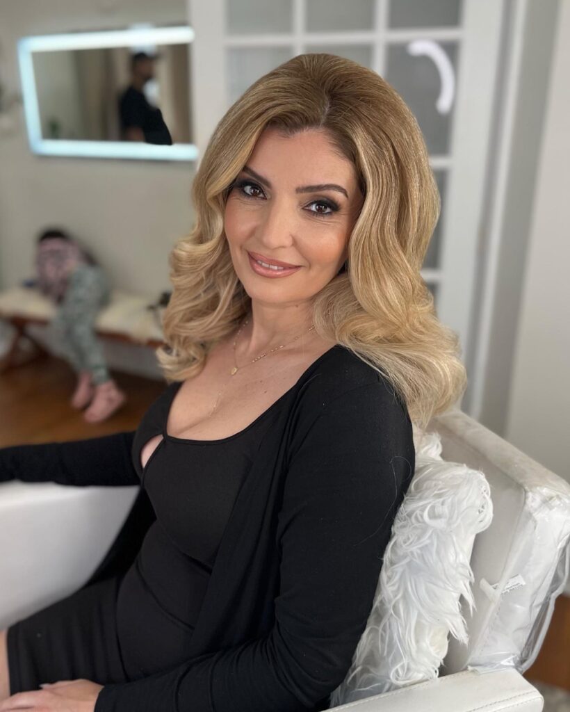 Medium length golden blonde hair styled in a glamorous voluminous blowout with soft waves.