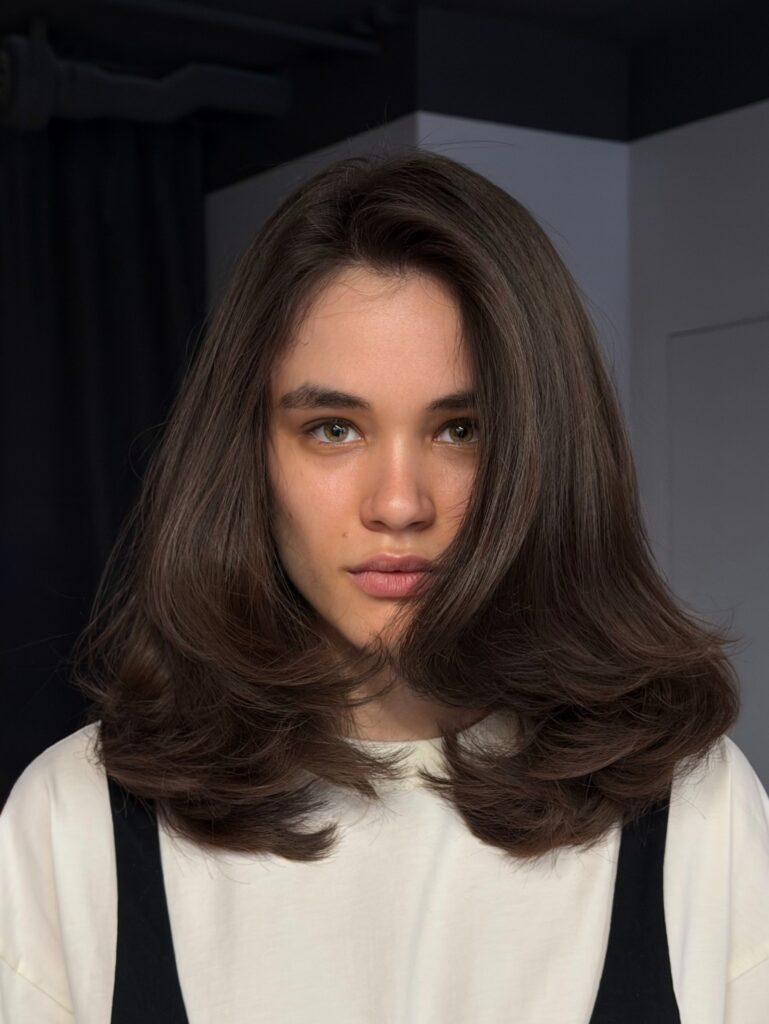 Medium length brunette hair with a center part and soft flipped out ends.