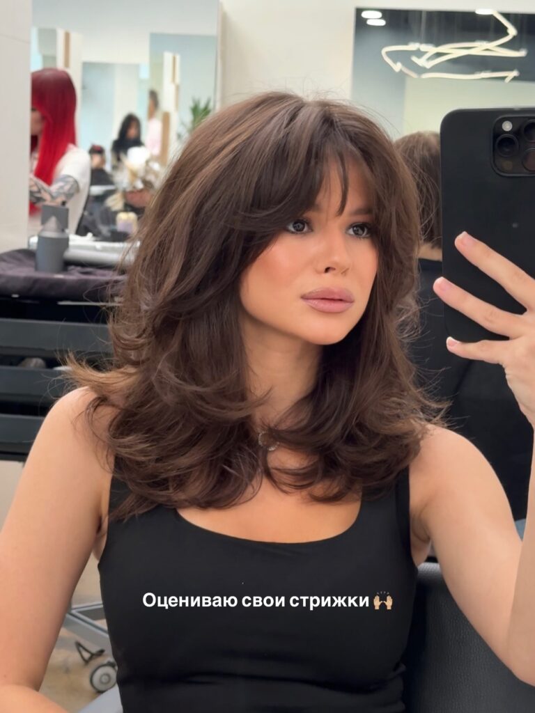 Shoulder length brown hair with wispy curtain bangs and flipped out layered ends.