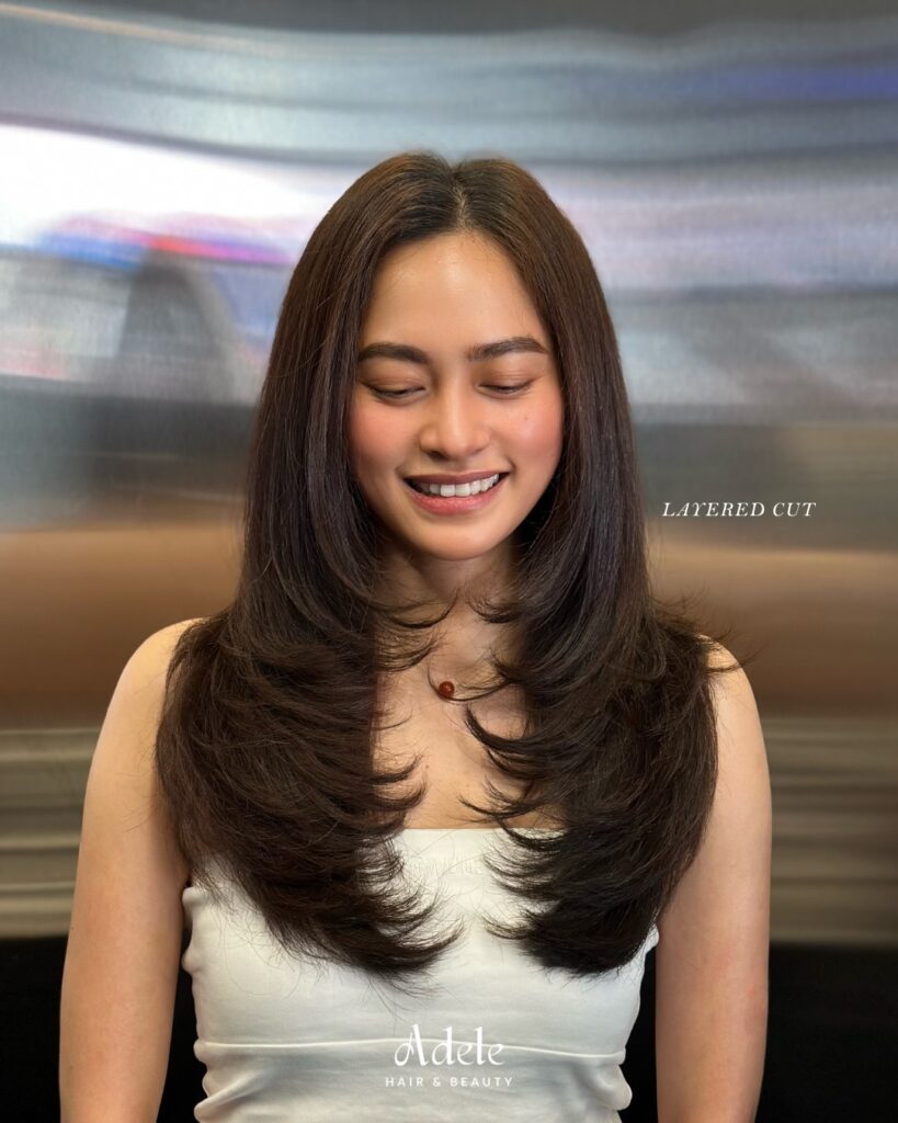 Long dark brown hair styled in feathery layers with playful, flicked-out wing tip ends.