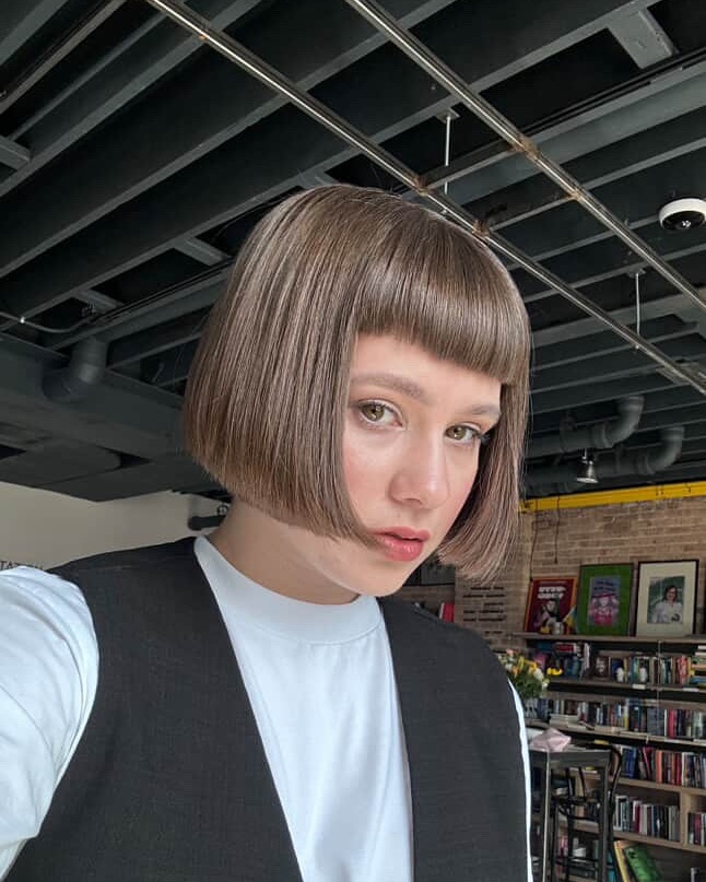 A woman with a sleek taupe brown blunt bob and a short micro fringe.