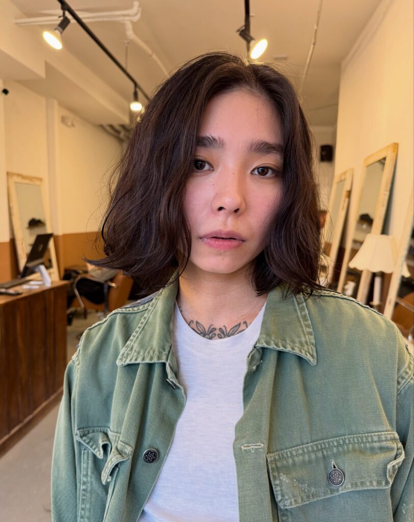 A woman with a shoulder length wavy dark brown bob and a soft middle part.