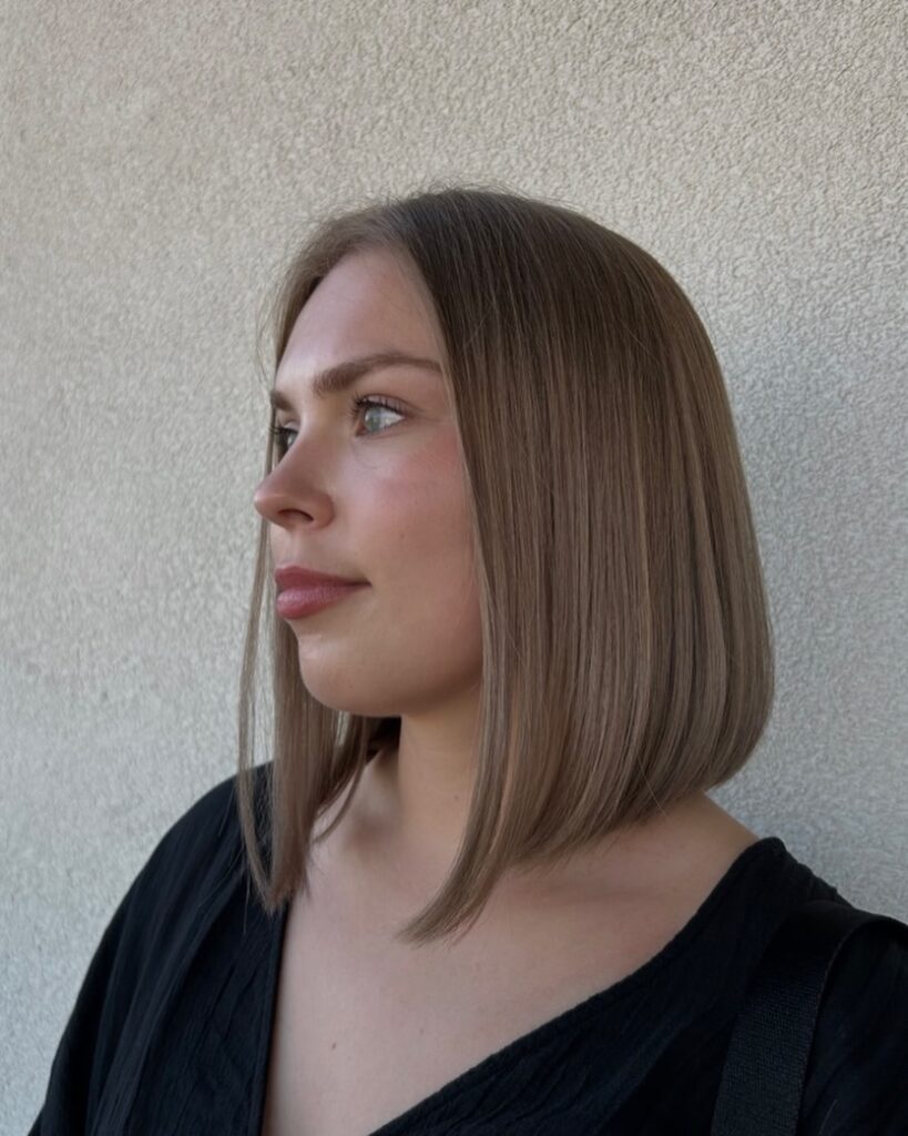 A woman with a sleek straight ash brown long bob with a subtle forward angle.