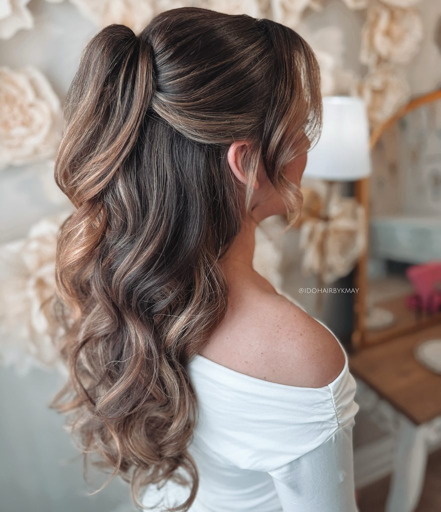 Long brunette hair styled in a high half up ponytail with soft curtain bangs and voluminous waves cascading down the back.