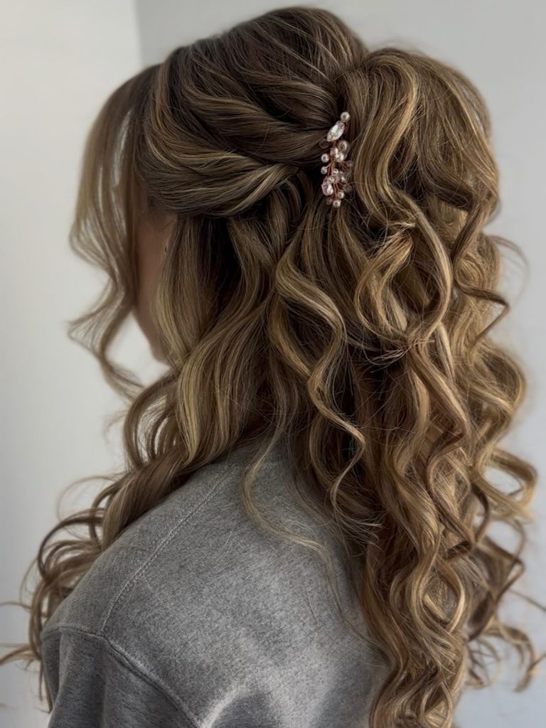 Long light brown hair styled with romantic twists in a half updo and a pearl hair clip.