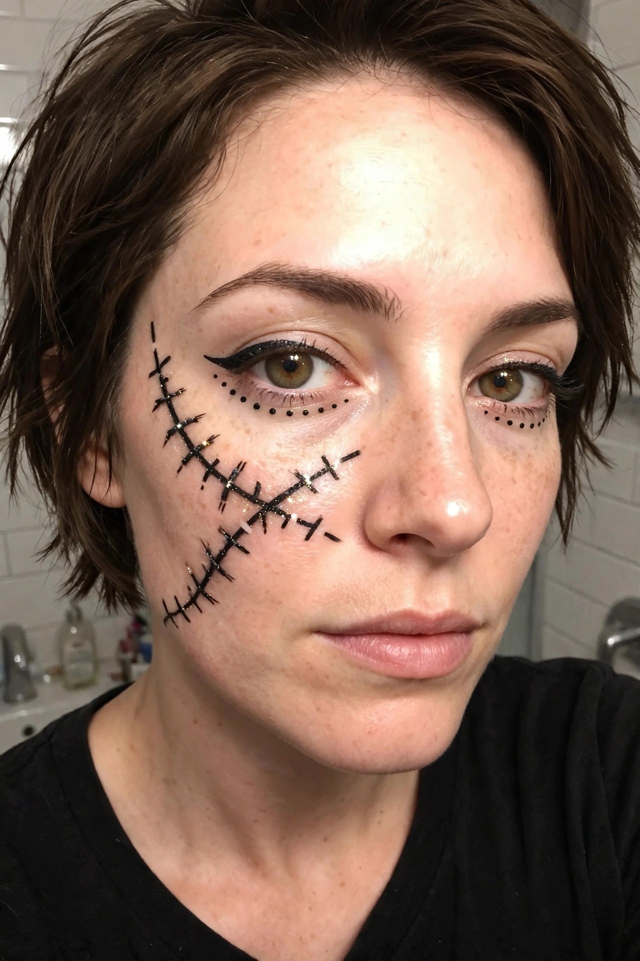 Close up of stitched scar makeup with black graphic liner and dotted under eye details on short brown hair.