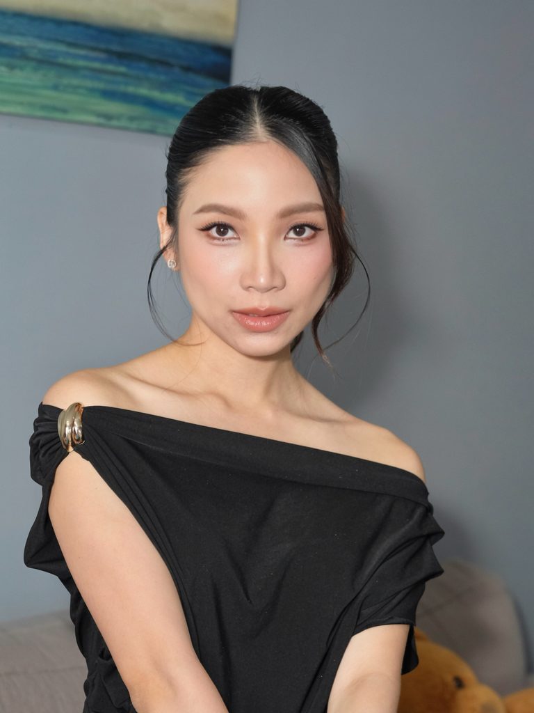Front view of a woman with jet black hair in a sleek center-parted updo with soft curled strands framing her face.