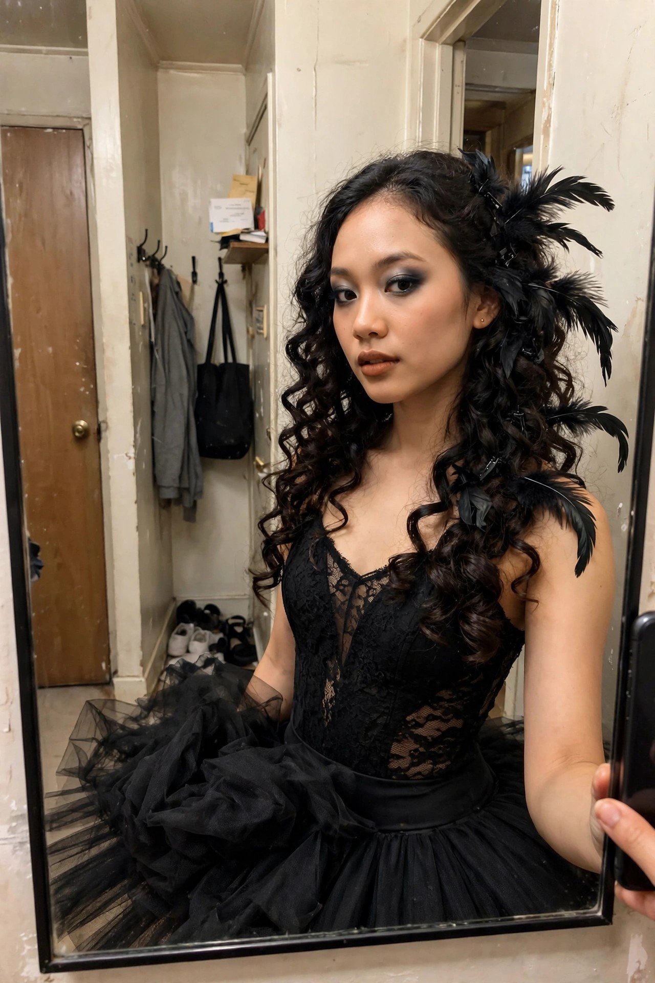 Woman wearing a black lace corset and voluminous black tulle tutu with black feathers clipped into long curly dark hair while taking a mirror selfie.