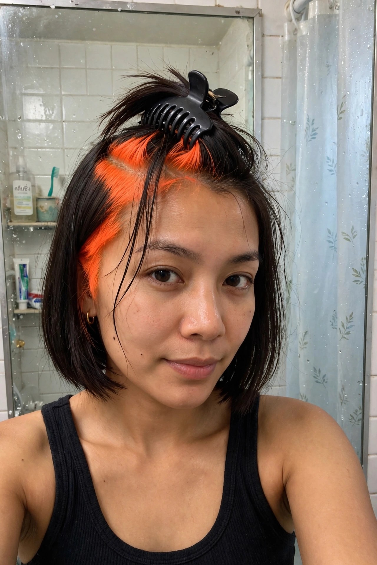 Close up of short dark bob with bold bright orange sections along the hairline and side part against the natural dark base.