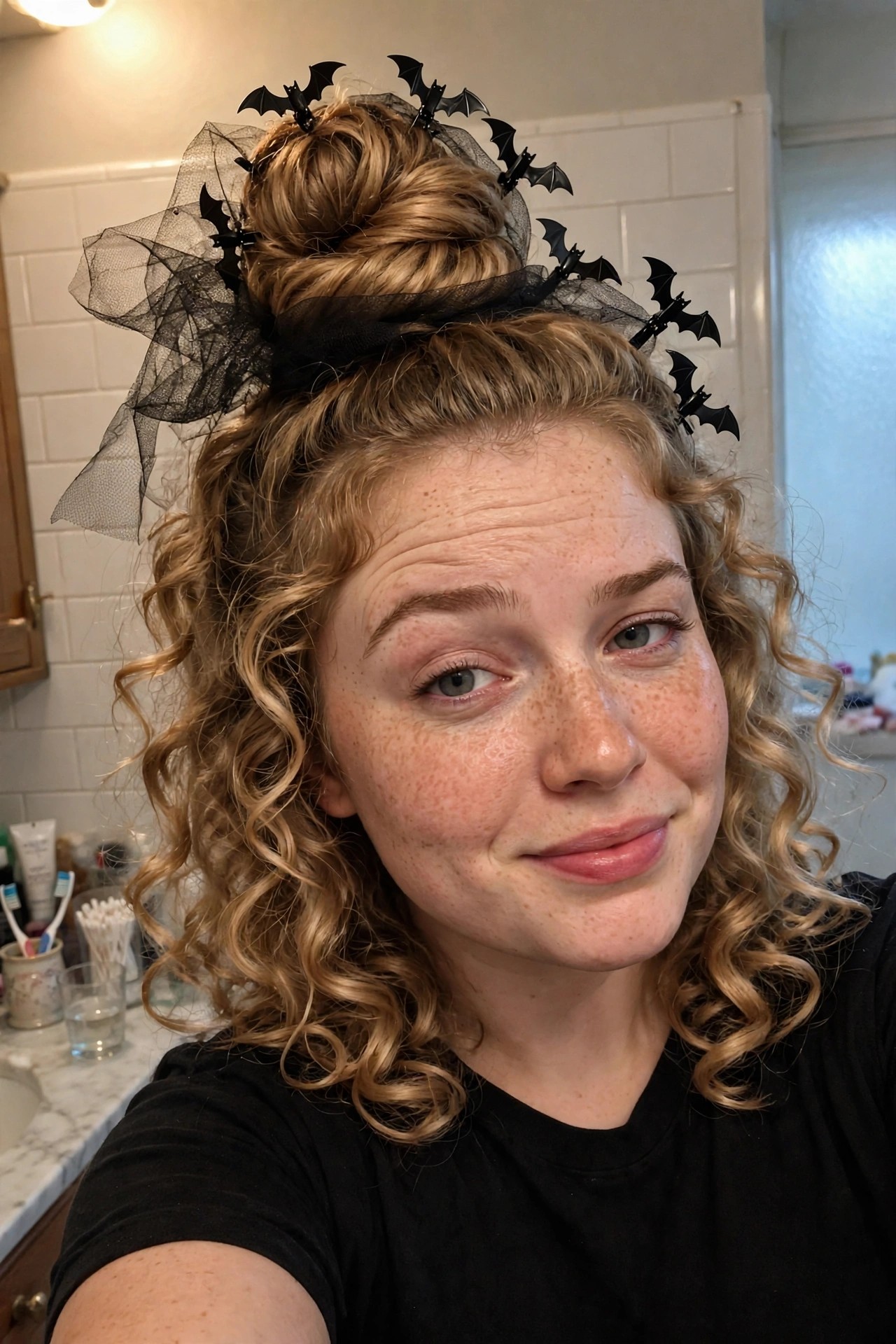Woman with curly blonde hair in a messy top bun decorated with black bat hair clips and black tulle fabric.