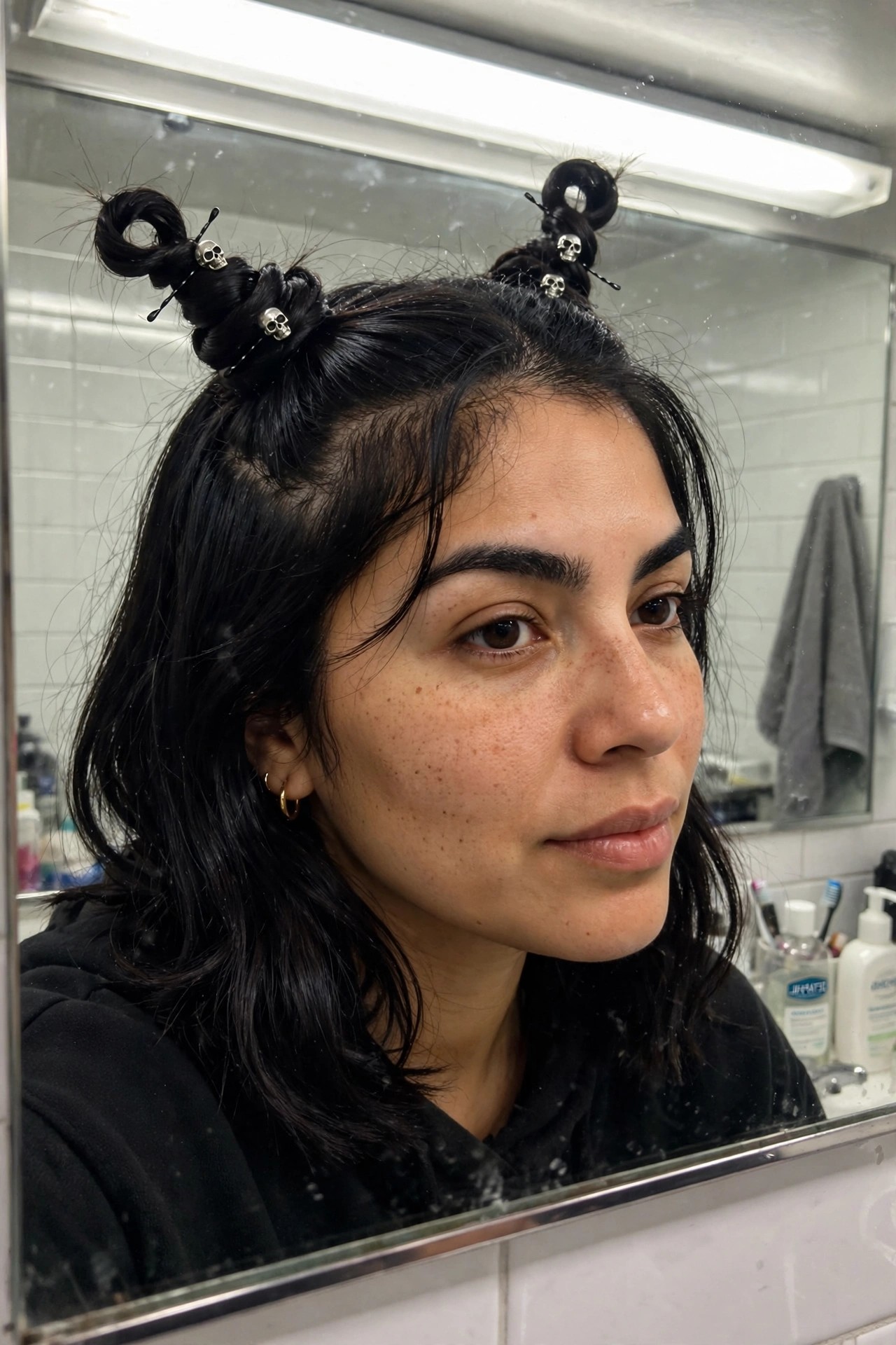 Woman with dark hair styled in multiple small topknots secured by silver skull hair clips and pins.