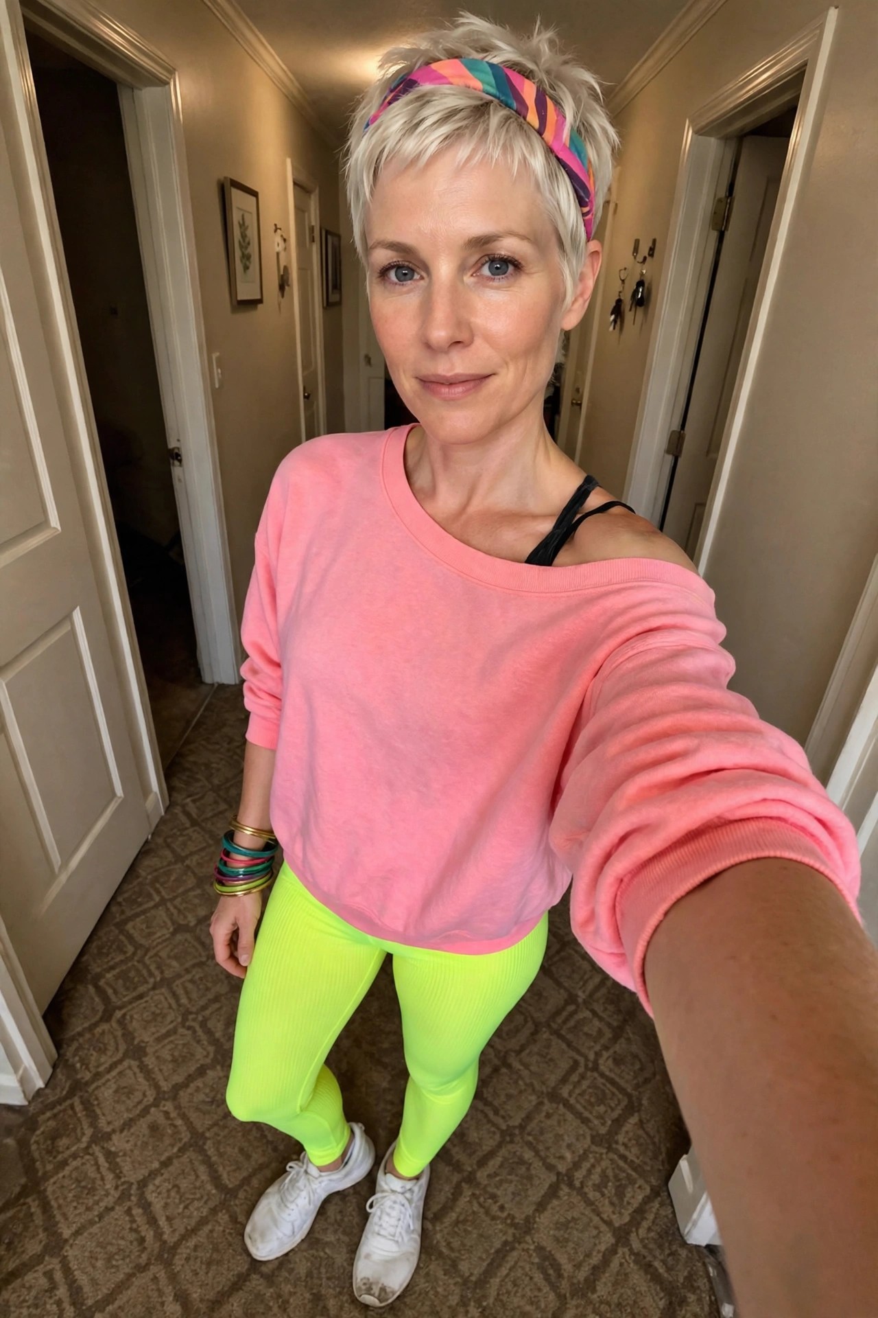 Woman wearing pink sweatshirt and neon yellow leggings with colorful striped headband for 80s aerobics instructor costume.
