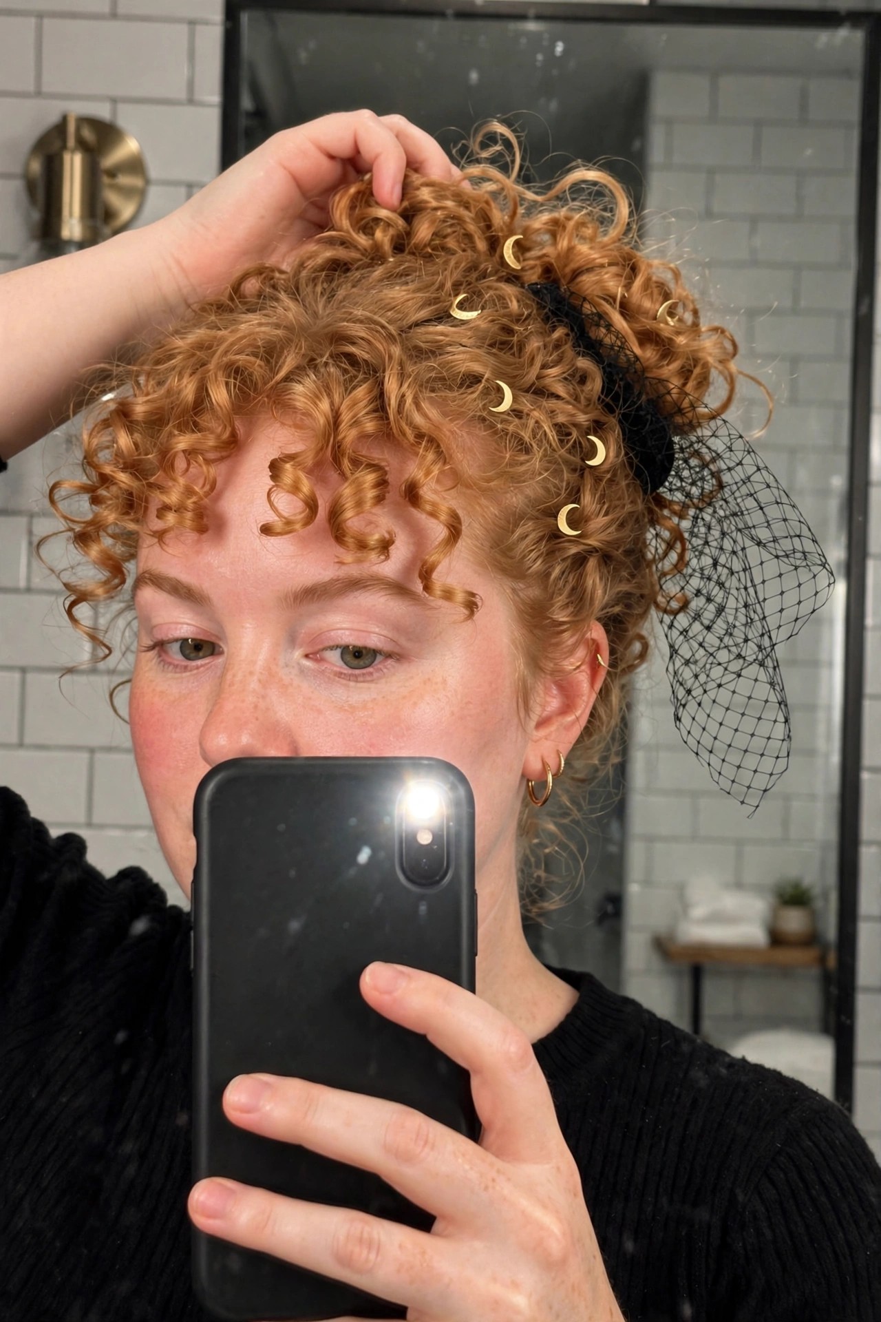 High curly red updo with scattered gold crescent moon clips and black mesh veil trailing from the bun.