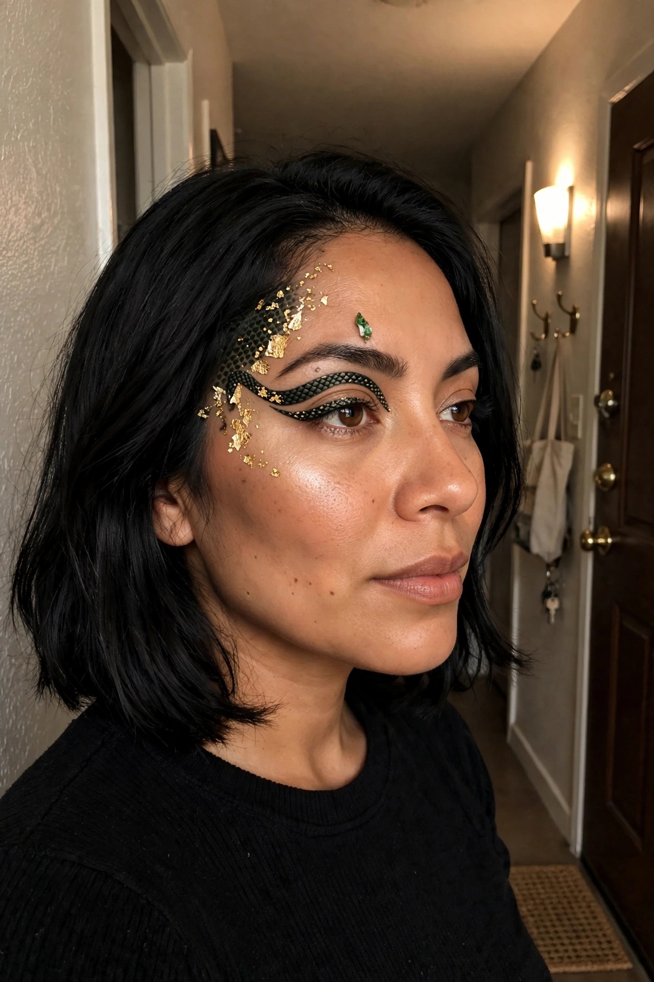 Close up of Medusa inspired makeup with black scale patterned eyeliner and scattered gold leaf flakes on the face.