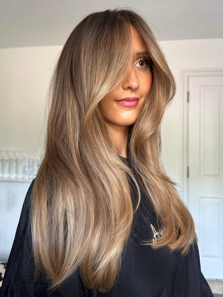  A woman with long, straight bronde hair and soft curtain bangs framing her face.